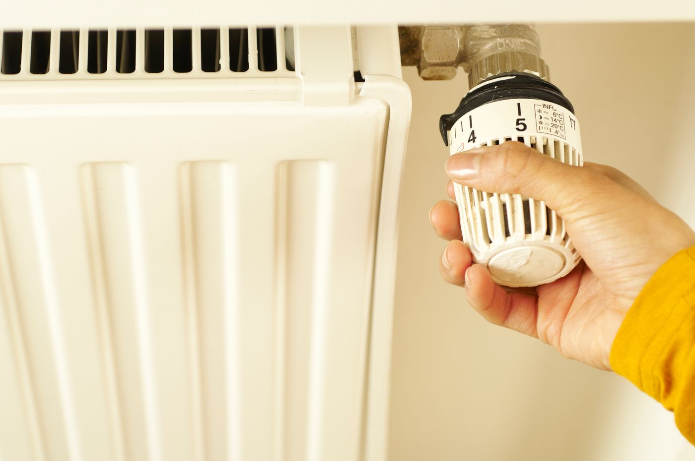 A hand adjusting a thermostatic radiator valve.
